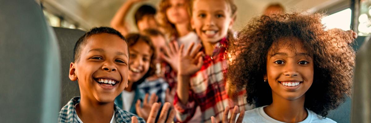 smiling kids waving on a bus